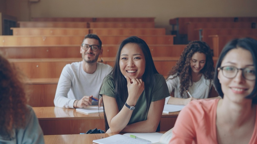Smiling students seated in a wood-panelled lecture hall