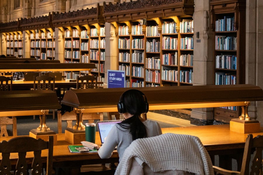 A student working on a laptop in a quiet library study area