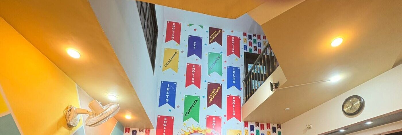 Course banners painted on the Qasimabad reception wall — English, PTE, IELTS, Computer, Career Counselling and Coaching
